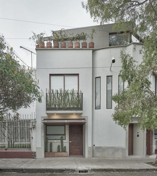 Moderno edificio residencial blanco en Pares Homes de la Ciudad de México con diseño minimalista, plantas verdes en balcón y madera