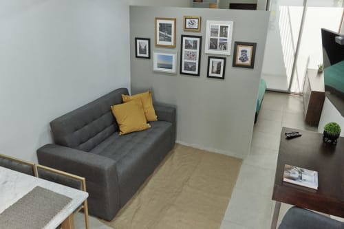 Sala de estar moderna en apartamento de Ciudad de México con sofá gris, cojines amarillos, galería de arte y pisos de madera en Pares Homes