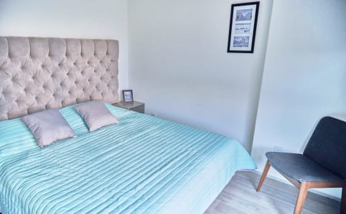 Recámara moderna en departamento Pares Homes, Ciudad de México, con ropa de cama turquesa, cabecera capitonada y decoración minimalista