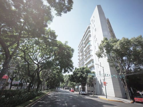 Edificio de apartamentos blanco moderno en calle arbolada de la Ciudad de México, propiedad de Pares Homes
