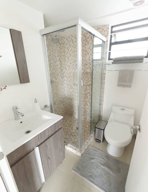 Baño moderno en apartamento de Pares Homes Ciudad de México con ducha de cristal, azulejos de mosaico, tocador blanco e inodoro