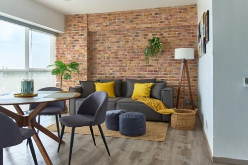 Apartamento moderno en Pares Homes, Ciudad de México con pared de ladrillo expuesto, sofá gris, detalles amarillos y vistas a la ciudad