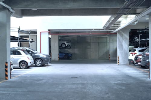 Estacionamiento subterráneo en el departamento Pares Homes de la Ciudad de México con múltiples vehículos y estructura de concreto
