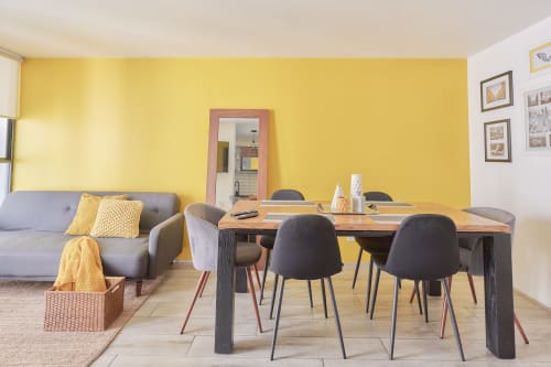 Moderno departamento CDMX en Pares Homes con paredes amarillas, comedor, sofá gris y acceso a cocina