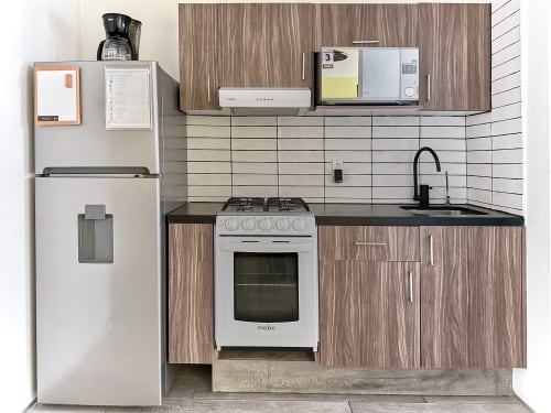 Cocina moderna y compacta en apartamento de la Ciudad de México en Pares Homes con estufa, fregadero, refrigerador y azulejos blancos tipo subway