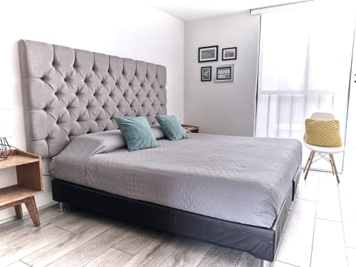 Recámara moderna en departamento Pares Homes CDMX con cabecera capitoné gris, ropa de cama clara, almohadas verde azulado y minimalista