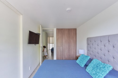 Recámara moderna en apartamento Pares Homes CDMX con ropa de cama azul, cabecera gris y almohadas turquesas
