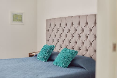 Recámara moderna en Pares Homes Ciudad de México con cabecera capitonada beige, ropa de cama azul y almohadas turquesas