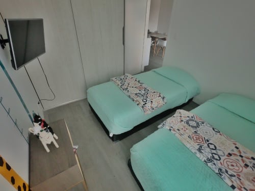 Vista aérea de camas gemelas con ropa de cama verde menta en apartamento Pares Homes, Ciudad de México
