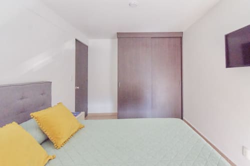 Recámara moderna en apartamento Pares Homes CDMX con clósets corredizos morados y almohadas amarillas