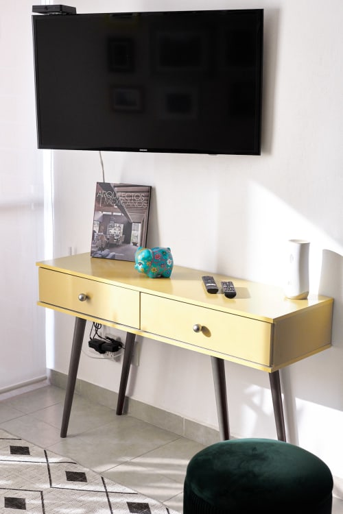 Escritorio amarillo de mediados de siglo con TV montada en pared en apartamento moderno de la Ciudad de México en Pares Homes