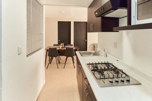 Cocina moderna con estufa de gas y área de comedor en apartamento Pares Homes en la Ciudad de México