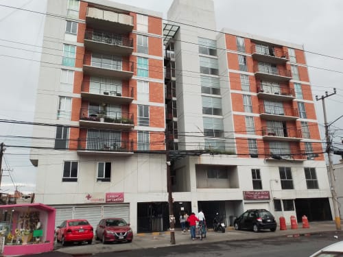 Edificio de apartamentos Pares Homes en CDMX con fachada de ladrillo rojo y beige, locales comerciales en planta baja y balcones