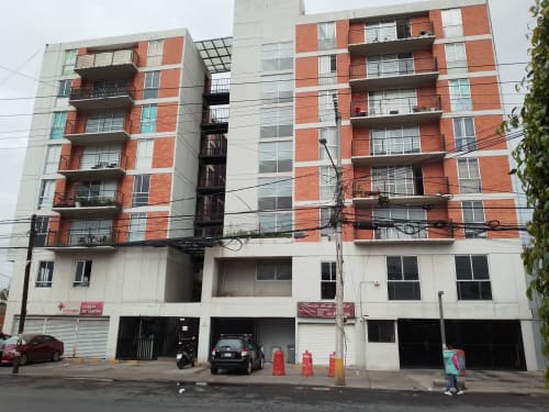 Edificio de apartamentos Pares Homes en Ciudad de México con fachada de ladrillo rojo y blanco, balcones y estacionamiento en planta baja