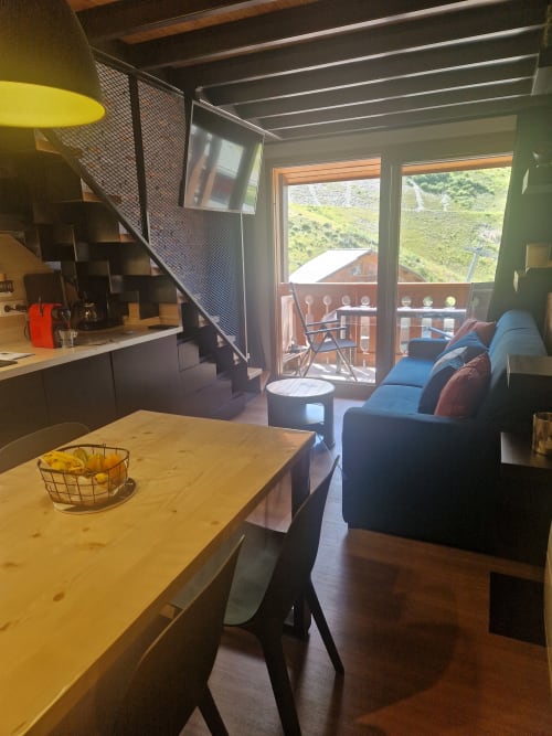Appartement moderne ouvert avec table à manger, cuisine et canapé bleu avec vue sur les montagnes à Méribel