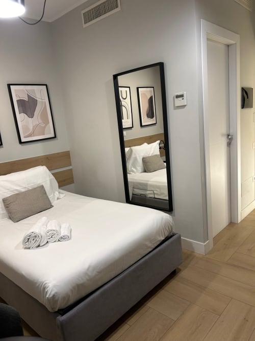 Camera moderna di Casa Lounge Istria, Cagliari con biancheria bianca, specchio con cornice nera e arte astratta a muro