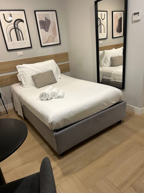 Camera moderna a Casa Lounge Istria a Cagliari con letto matrimoniale, biancheria bianca, testata in legno e arte murale astratta