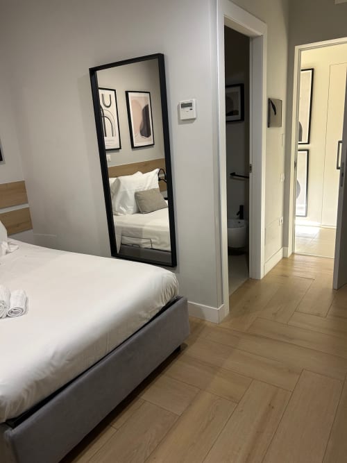 Camera moderna a Casa Lounge Istria, Cagliari con specchio a figura intera, biancheria bianca e pavimento in legno