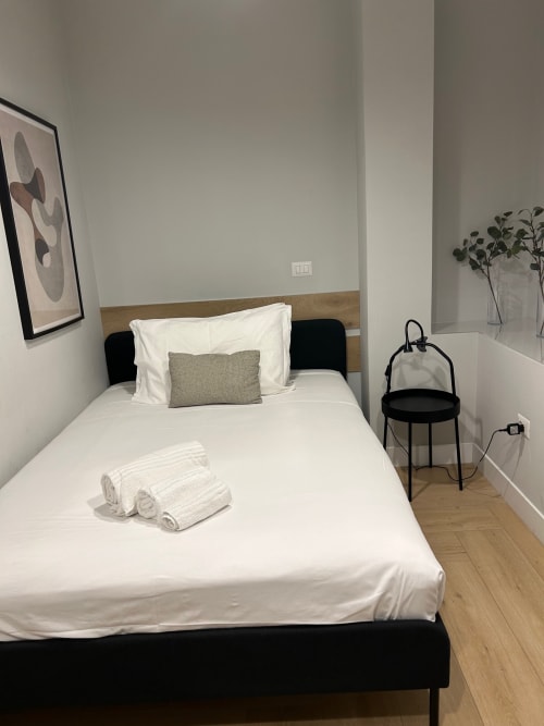 Camera moderna di Casa Lounge Istria a Cagliari con biancheria bianca, testata in legno e vista sulla città