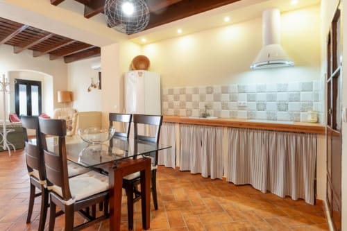 Cocina y comedor integrados en Villas Vacacionales Sevilla con baldosas de terracota, vigas de madera y azulejos decorativos