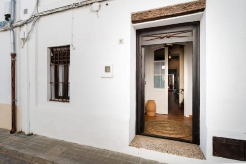 Villa encalada en Salteras con puerta de madera oscura, ventana enrejada y entrada rústica a Villas Vacacionales
