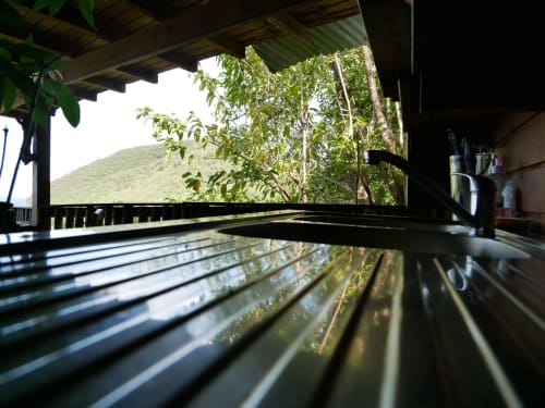 Terrasse en bois de la villa Les Hauts De Deshaies avec vue sur les montagnes et végétation luxuriante à Deshaies