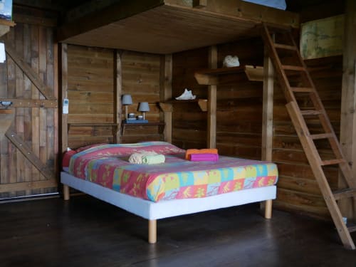 Chambre rustique à Les Hauts De Deshaies avec literie colorée, étagères en bois et accès par échelle à Deshaies