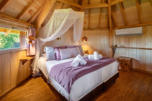 Mayreau-kamer in Domaine De Campagnac met hemelbed, paarse beddengoed, houten balken en airconditioning in Carsac-Aillac