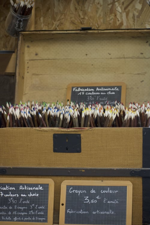 Lápices de colores artesanales expuestos en la tienda Baccara Lodge en Arengosse, Francia con cartel de precios