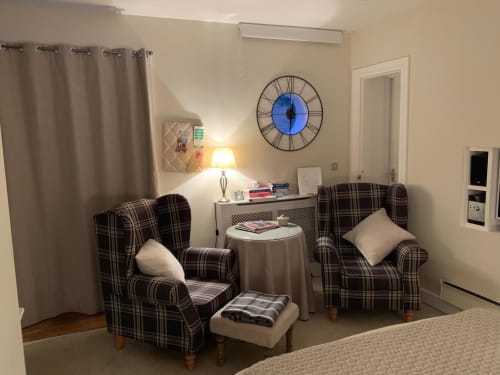 Cozy seating area at Grapevine Studio, Waterbeach with plaid armchairs, blue clock, and warm lighting.