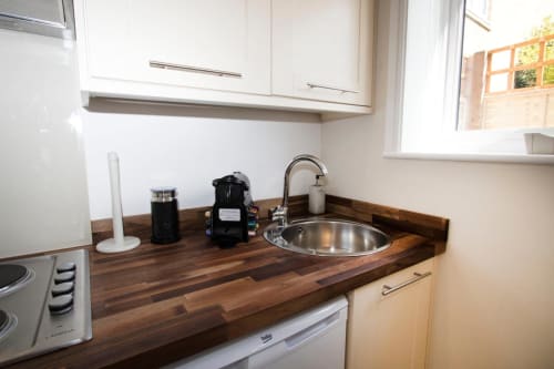 Modern kitchenette at Grapevine Studio with wooden countertop, stainless steel sink, white cabinets, and appliances in