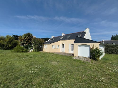 Adorable maison familiale crème à Locmaria, Belle-Île-en-Mer, toit noir et garage blanc, entourée de verdure
