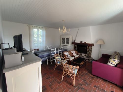 Spacieux séjour avec salle à manger, cheminée, canapé rose et vue jardin à Loc'Maria, Belle Île en Mer