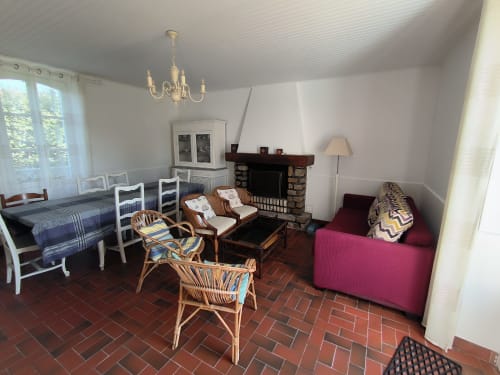 Séjour chaleureux de cottage familial avec cheminée, table à manger et canapé bordeaux à Locmaria Belle Île en Mer