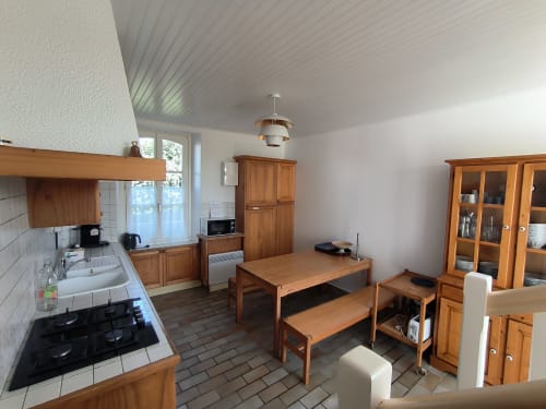 Cuisine lumineuse et coin repas avec mobilier en bois, cuisinière à gaz et appareils modernes à Locations Loc'Maria, Belle
