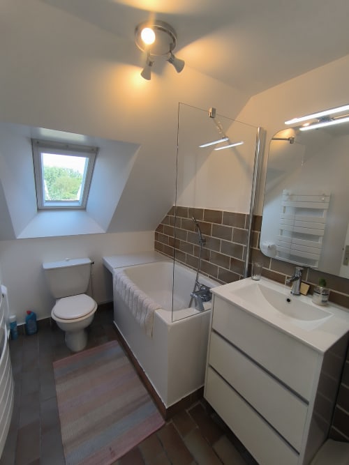 Salle de bain moderne du gîte Belle Île en Mer avec vasque blanche, cabine de douche vitrée, puits de lumière et sèche-serviettes électrique