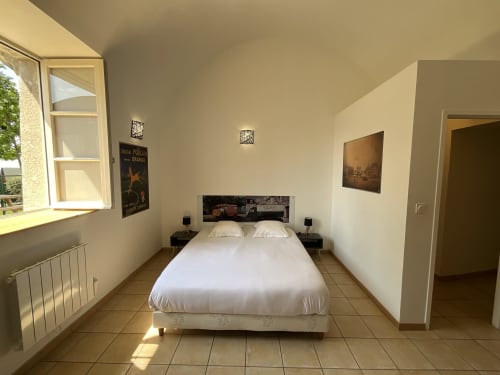 Bright bedroom in Locacharme cottage, Blois with queen bed, white linens, tiled floors, and garden view window