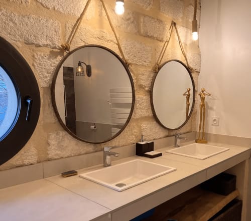 Salle de bain luxueuse avec vasques doubles, miroirs ronds et murs en pierre au MAS PETIT CORBIERE à Aigues-mortes gite