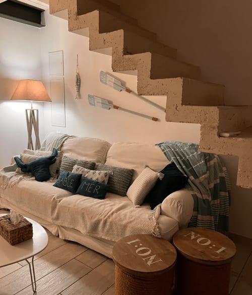 Chambre cosy de la maison d'hôtes Adelouane à Aigues-mortes : lit crème, escalier en liège, lampe et tabourets en bois
