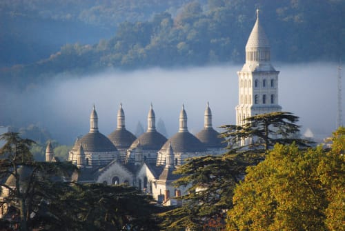 Sacré-Cœur Basilica with domed towers and bell tower overlooking misty valleys near Carsac-Aillac, France