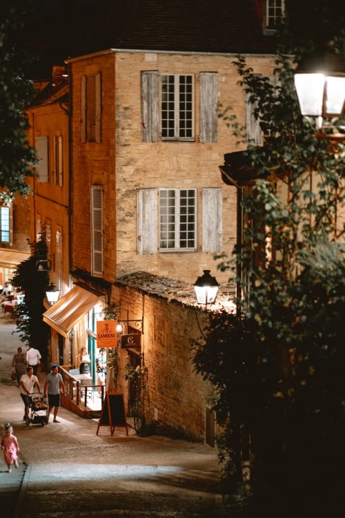 Charming nighttime street view of Domaine De Campagnac B&B in Carsac-Aillac, France, with stone buildings and ivy-covered
