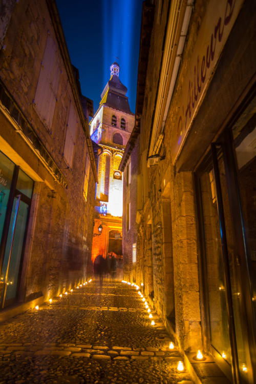 Medieval stone street in Carsac-Aillac with illuminated bell tower at twilight