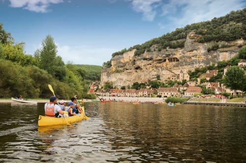Family kayaking on river with medieval village cliffs, Carsac-Aillac Dordogne