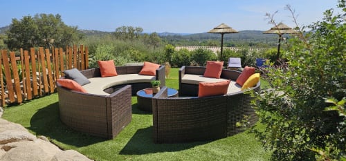 Luxurious villa lounge at Villas-Majos Corsica with curved wicker seating, orange pillows, fire pit, and Mediterranean garden