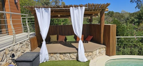 Luxurious pergola lounge with white curtains, cushioned seating, and stone walls at Villas-Majos in Porto-Vecchio