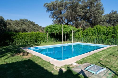 Piscina rectangular con cubierta azul en la villa Casa Rural Ribera del Hueznar en Constantina, rodeada de setos verdes