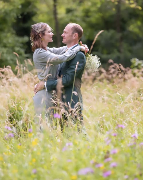 Pareja elegante abrazándose en un prado de flores silvestres en Domaine de l'Ocrerie, Pourrain