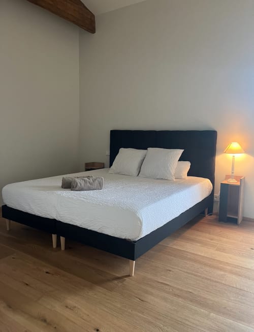 Modern bedroom in Les FOUDRES villa at La Conciergerie De Franck with dark headboard bed, white bedding, and warm lamplight