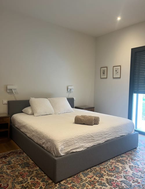 Modern bedroom at La Conciergerie De Franck villa with gray bed, cream bedding, and pool view access in Boissieres