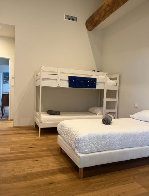 Modern bedroom with white bunk bed and queen bed on wooden floor at La Conciergerie De Franck villa